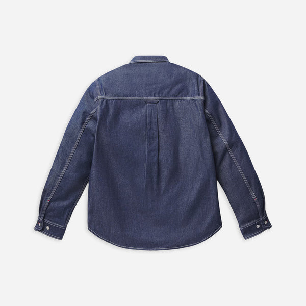 A dark blue denim long-sleeve shirt shown from the back, featuring contrast stitching and a curved hem, laid flat against a light gray background.