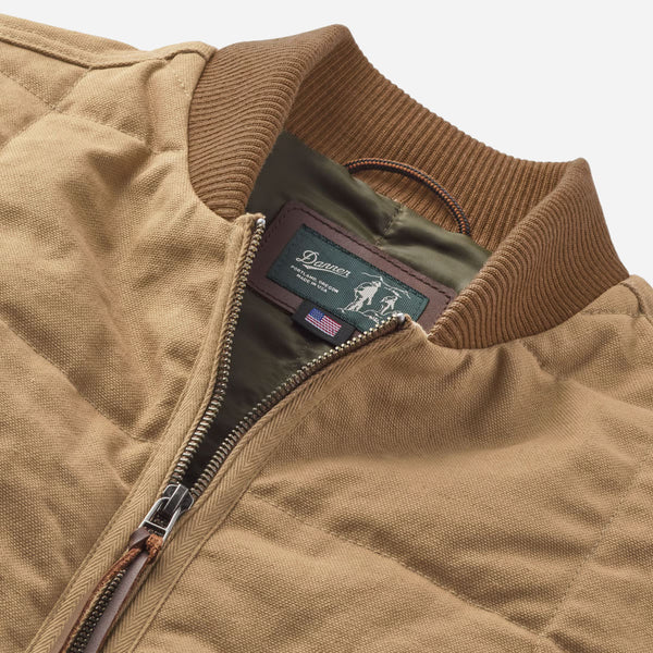 Close-up of a brown jacket with a brand label on a light gray background