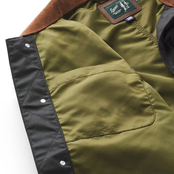Close-up of a green jacket with brown lining and brand label on a white background