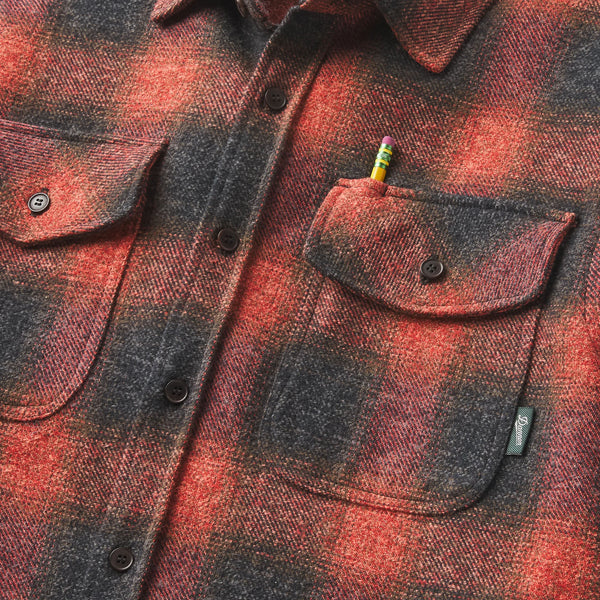 Red and black plaid shirt with a colorful pencil in the pocket