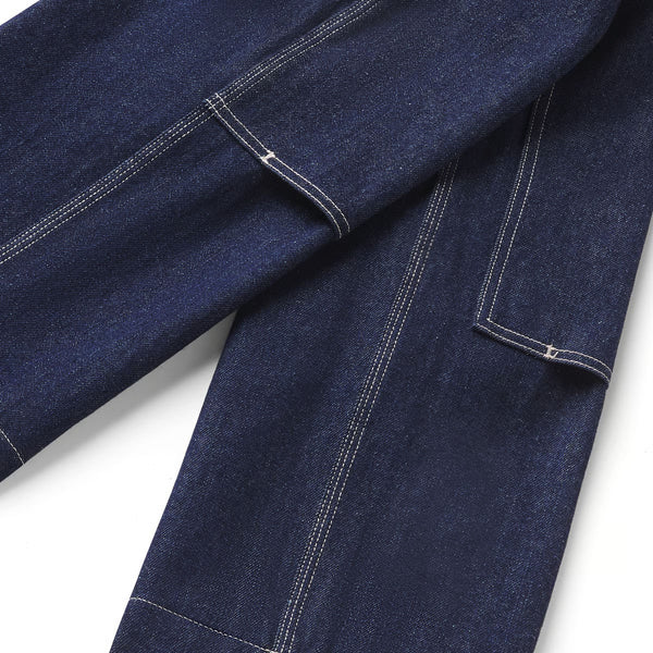 Close-up of dark indigo denim fabric with white contrast stitching, showing part of a pocket and seam detail on a white background.