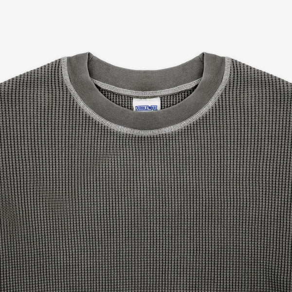 Close-up of a dark gray waffle-knit crewneck sweater with a ribbed collar and a visible Dri-Wax label inside the neckline.