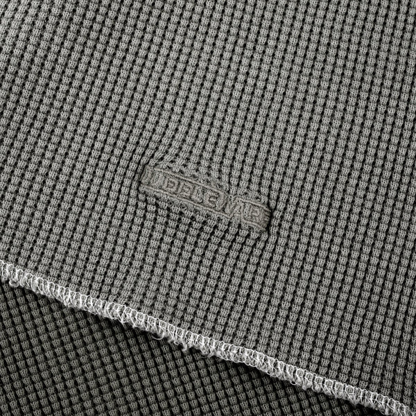 Close-up of a gray textured fabric with a visible woven brand patch reading 'BELLEWE' and a folded edge showing the material texture.