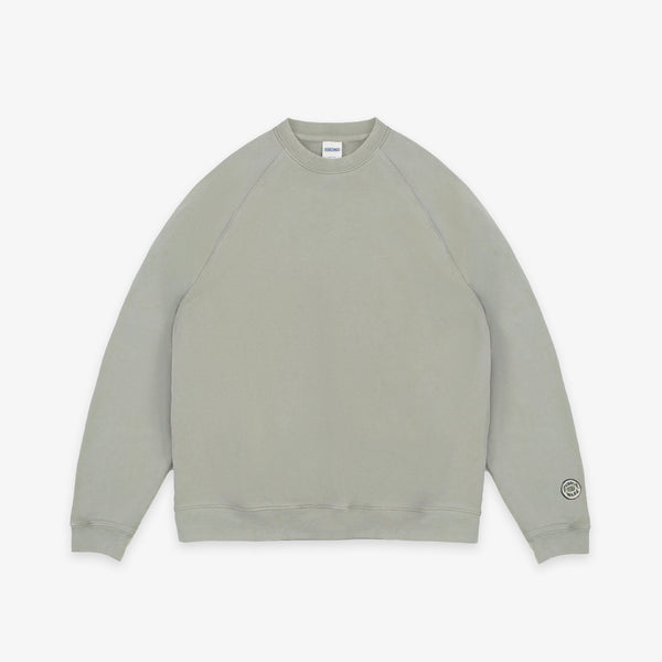 A light sage green crewneck sweatshirt with raglan sleeves, laid flat against a clean white background.