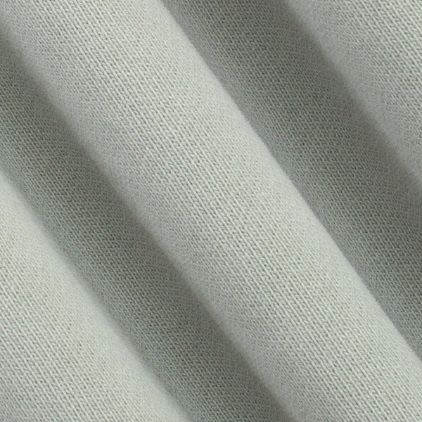 A close-up of draped light sage green knit fabric showing its fine woven texture and soft folds.