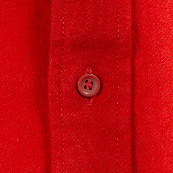 Close-up of a bright red button-down shirt fabric with a matching red button on the placket.