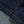 Load image into Gallery viewer, Close-up of dark indigo denim fabric with orange contrast stitching and a lighter gray denim section folded over.
