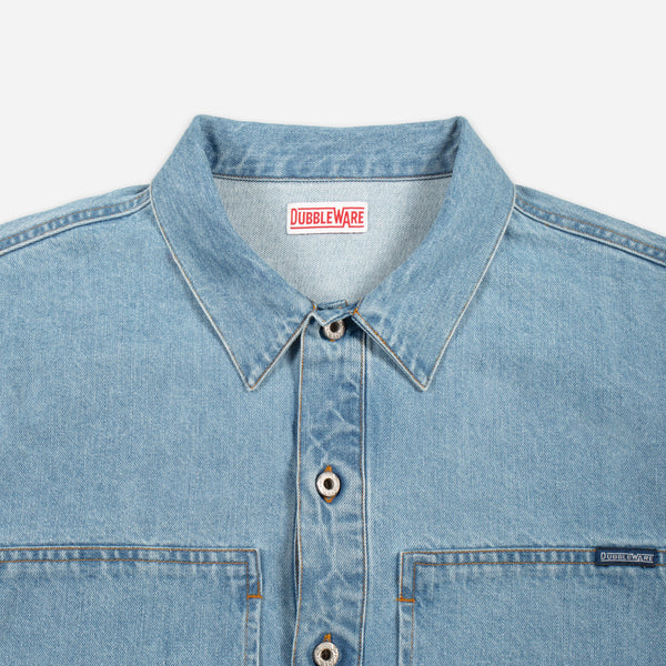 Close-up of a light blue denim button-up shirt collar and chest area, showing the Doubleware brand label inside the neck and a small Doubleware tag on the chest pocket.