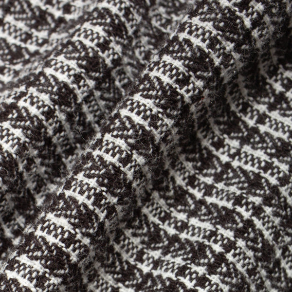 Close-up of a textured knit fabric with a black and off-white woven pattern, showing the detailed weave and soft folds.