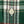 Load image into Gallery viewer, Close-up of a green plaid fabric with white, gray, and red stripes, featuring a single cream-colored button on the placket.
