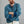 Load image into Gallery viewer, A man with red hair and a beard wearing a textured blue henley shirt with contrasting dark blue cuffs, posed with arms crossed against a solid gray background.
