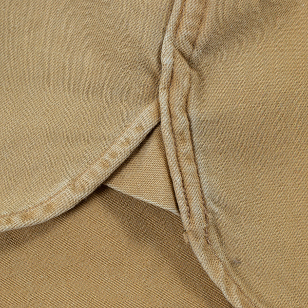 Close-up of a tan or khaki woven fabric with visible stitching and a folded corner.