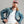 Load image into Gallery viewer, A man wearing a dusty pink baseball cap, a blue denim jacket with a brown corduroy collar over a white t-shirt, and cream-colored pants, posing against a solid gray studio background.

