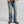 Load image into Gallery viewer, A person wearing light-wash blue denim jeans with a tan overshirt and dark brown boots, shown from the waist down against a plain light gray studio background.
