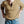 Load image into Gallery viewer, A man wearing a textured, long-sleeve Henley shirt in a warm olive-brown color, tucked into blue jeans, shown from the chest down against a neutral gray background.
