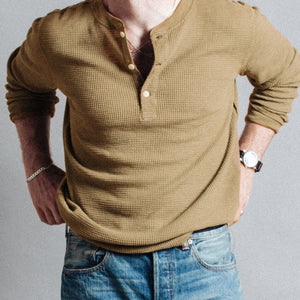 Double RL By Ralph Lauren - Garment-Dyed Waffle Henley T-Shirt - Spring Beige - A man wearing a textured, long-sleeve Henley shirt in a warm olive-brown color, tucked into blue jeans, shown from the chest down against a neutral gray background. - Alternative View 1