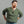 Load image into Gallery viewer, A man with a red beard wearing an olive green ribbed long-sleeve henley shirt and blue jeans, posing with hands on hips against a solid gray background.
