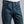 Load image into Gallery viewer, Close-up of a person wearing dark blue denim jeans with a white t-shirt tucked in, against a plain gray background.
